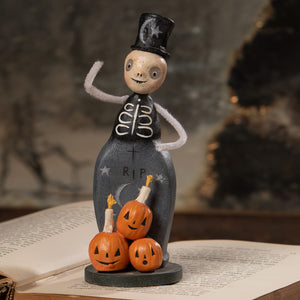 A whimsical halloween figural decor trickster skeleton with black top hat on tombstone base surrounded by jack o lanterns