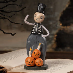 A whimsical skeleton trickster figurine in black top hat and vest with three orange jack-o-lanterns halloween figural decor