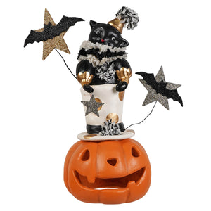 Black cat figurine with gold accents wearing a pom-pom hat and ruffled collar holding glittery jack o lantern decorations