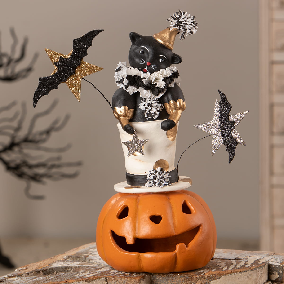 Black cat figurine wearing a gold party hat and white collar with glittery bats and stars for jack o lantern decor