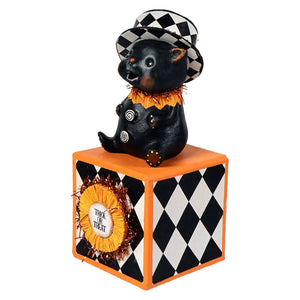 Black cat kitty boo figurine with checkered top hat and orange tinsel collar sitting on orange block with diamond pattern