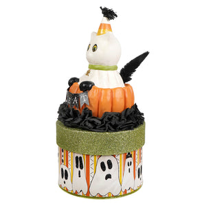 A white ceramic casper cat figurine with candy corn hat on an orange pumpkin atop a halloween cats box