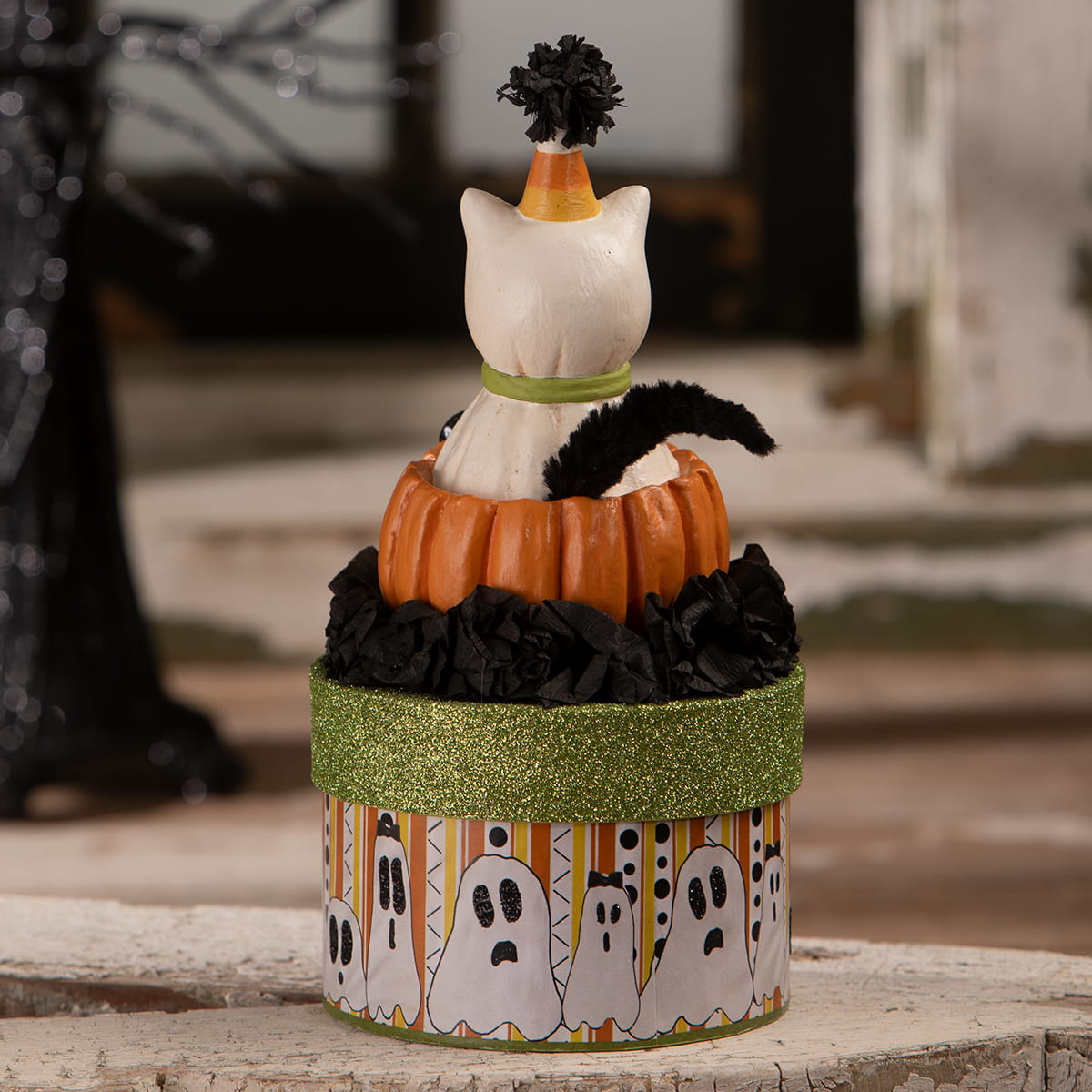A white ceramic casper cat figurine with a candy corn hat on an orange pumpkin box with halloween cats theme