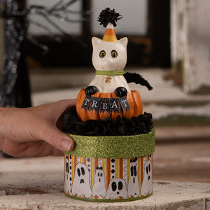 A white ceramic halloween cats figurine named casper with candy corn hat sits on a pumpkin inside a ghost box