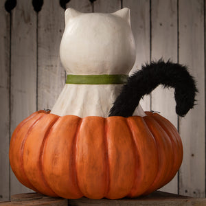 White casper cat figurine with green collar and black fuzzy tail sitting on orange pumpkin for trick or treat halloween cats