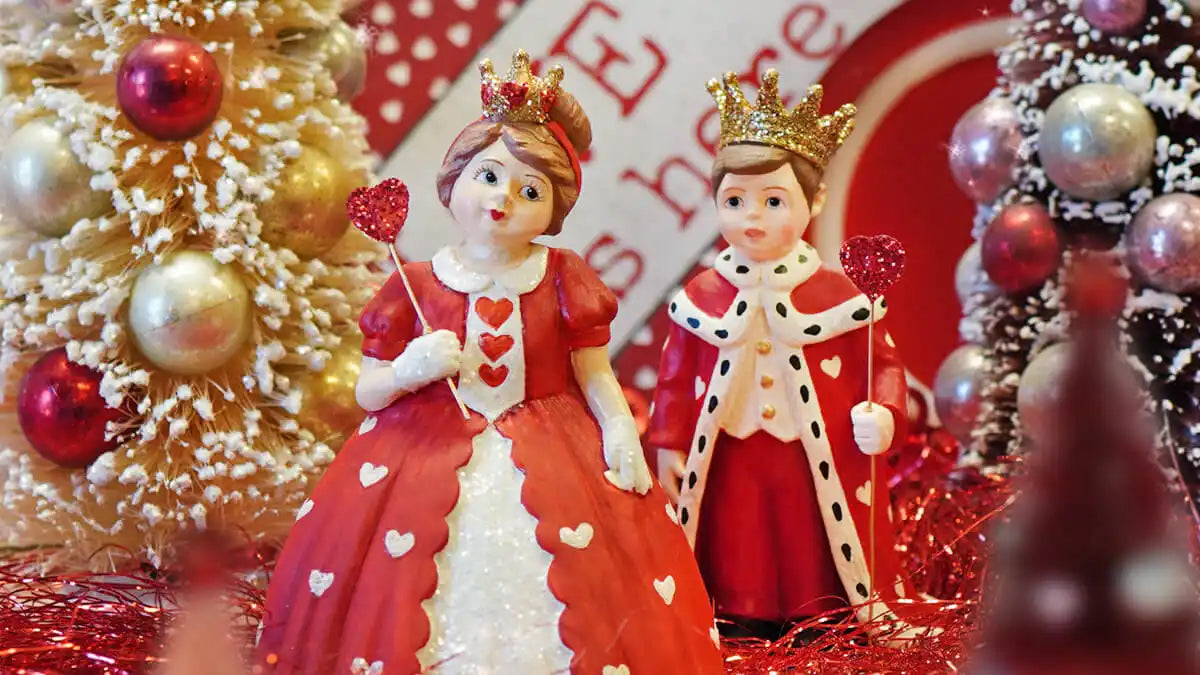 Two decorative royal figurines wearing red and white heart-adorned costumes and golden crowns.