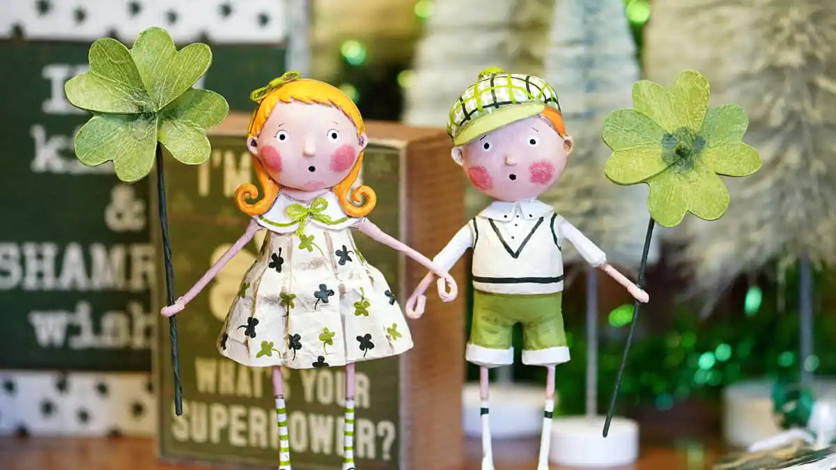 Two whimsical St. Patrick’s Day figurines holding shamrock decorations.