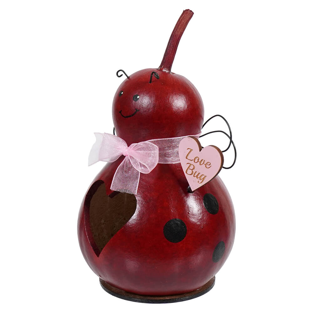 Red ladybug-shaped decorative gourd with a pink bow and heart tag.