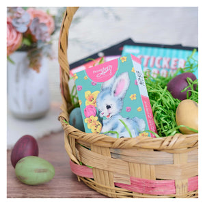 A pastel blue bunny themed sticker book with pink accents and floral designs in a wicker basket for retro easter puzzle fans