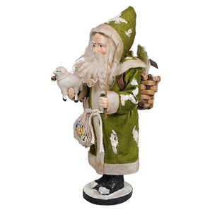 Traditional-style Christmas figurine wearing a green robe with white trim and carrying a staff and basket.