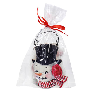 Snowman ornament with a black top hat and red scarf in a clear gift bag tied with a red ribbon.