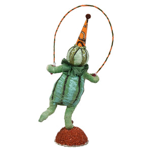 A handcrafted folk art scared pumpkin figure made of paper mache shaped like a green pumpkin holding a jump rope