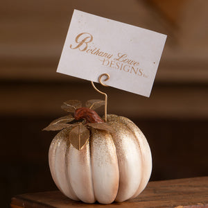 A glittery white and gold pumpkin placecard holder with metallic stem and leaf accents perfect for halloween pumpkins and gourds