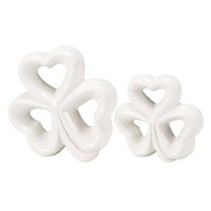 White ceramic shamrock or clover-shaped decorative objects with heart-shaped cutouts.