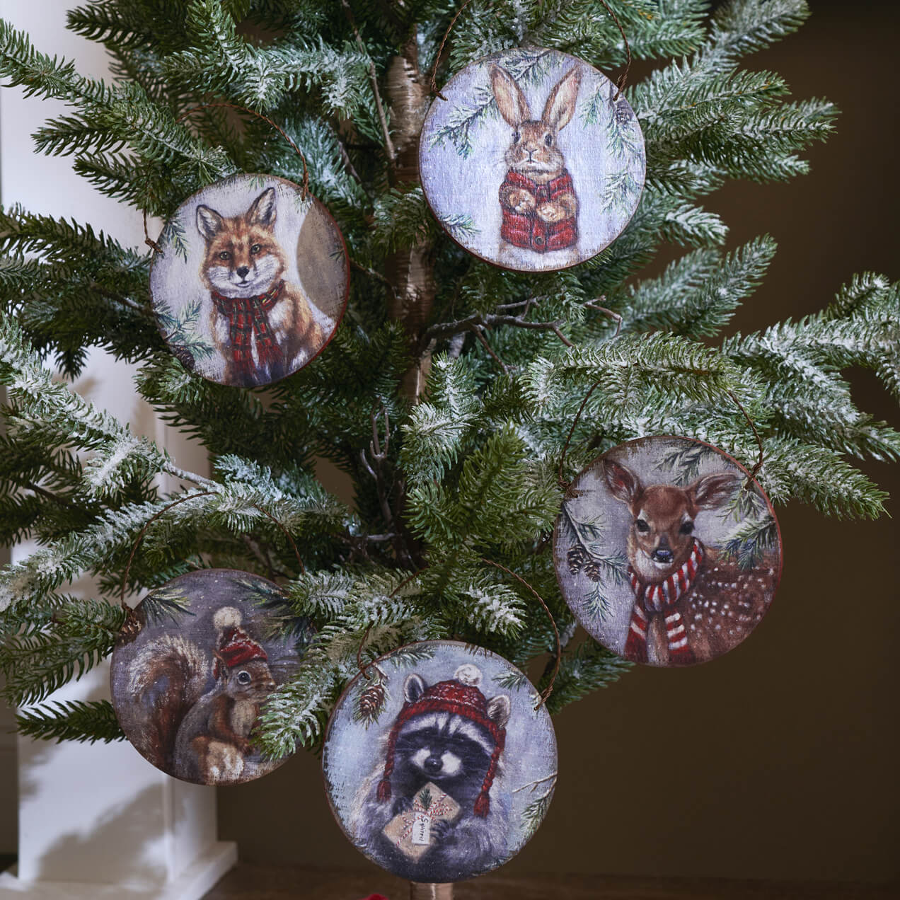 Christmas tree decorated with ornaments featuring woodland animal portraits.