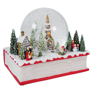 Christmas snow globe scene set on a decorative book base.