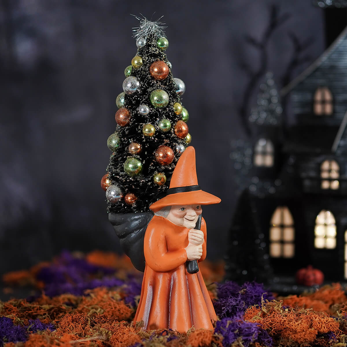 Orange witch carrying tree figurine with decorated christmas tree on her back perfect for halloween witches decor
