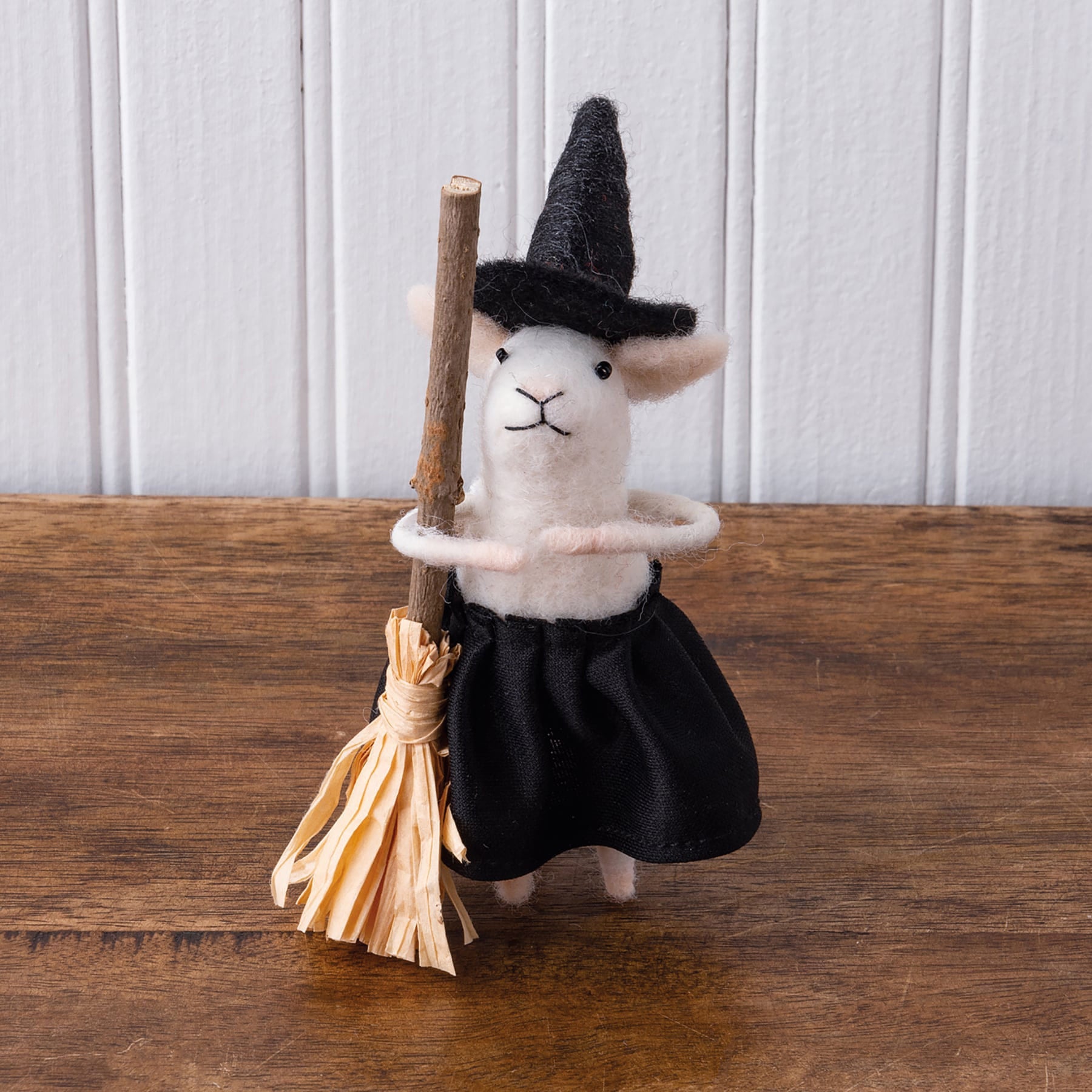 A white felt witch mouse critter wearing a black hat and skirt holding a broomstick from kathy’s halloween collection