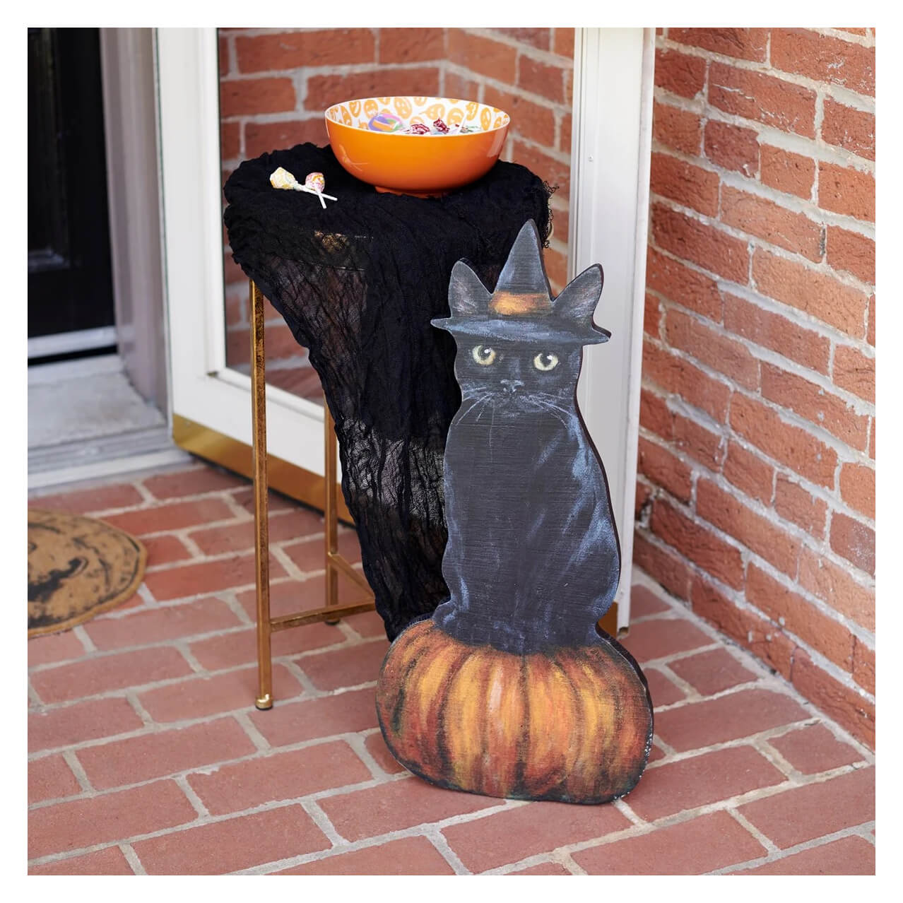 Cutout of a black cat wearing a witch’s hat sitting on a pumpkin.