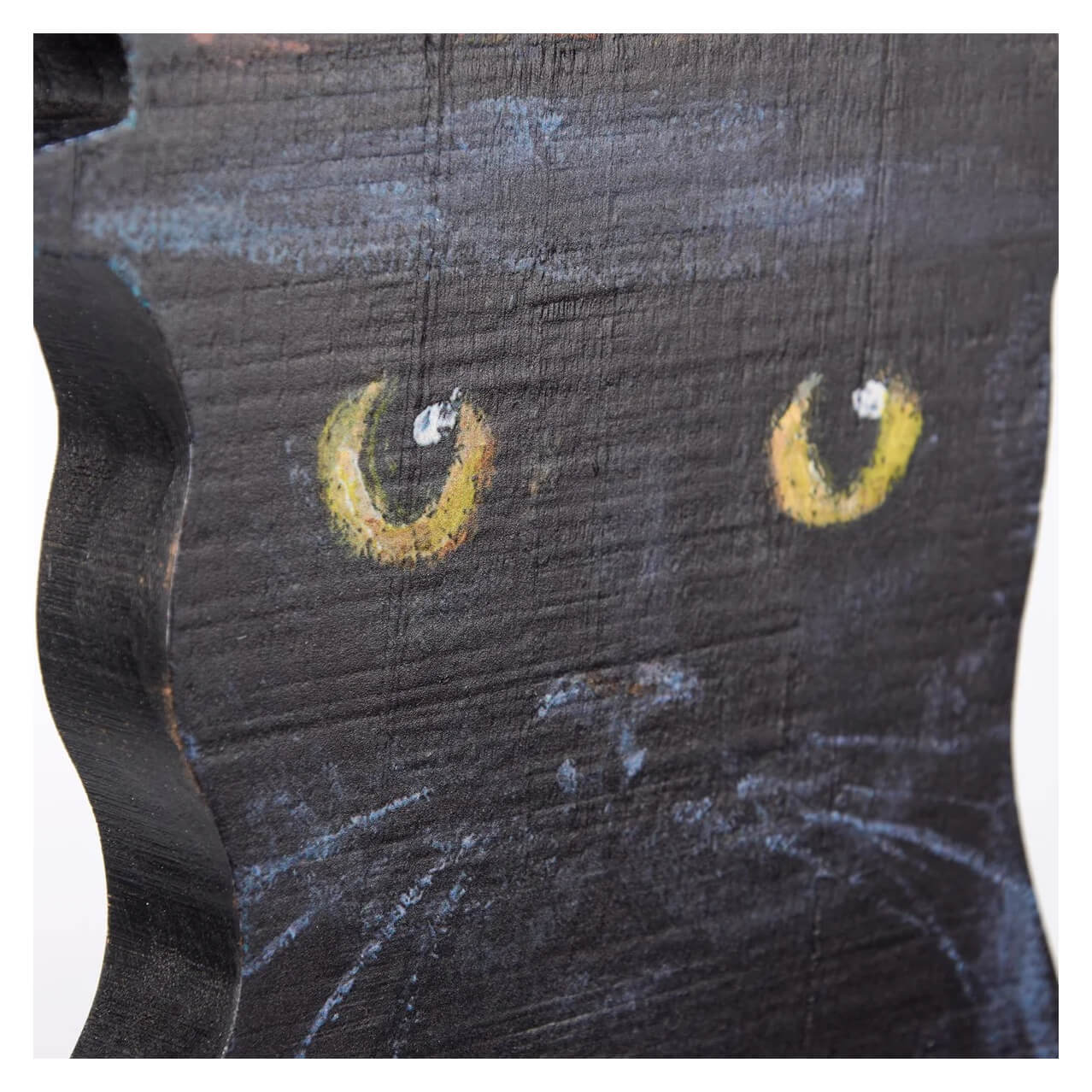 Wooden surface with painted yellow cat-like eyes and a curved line resembling a smile.