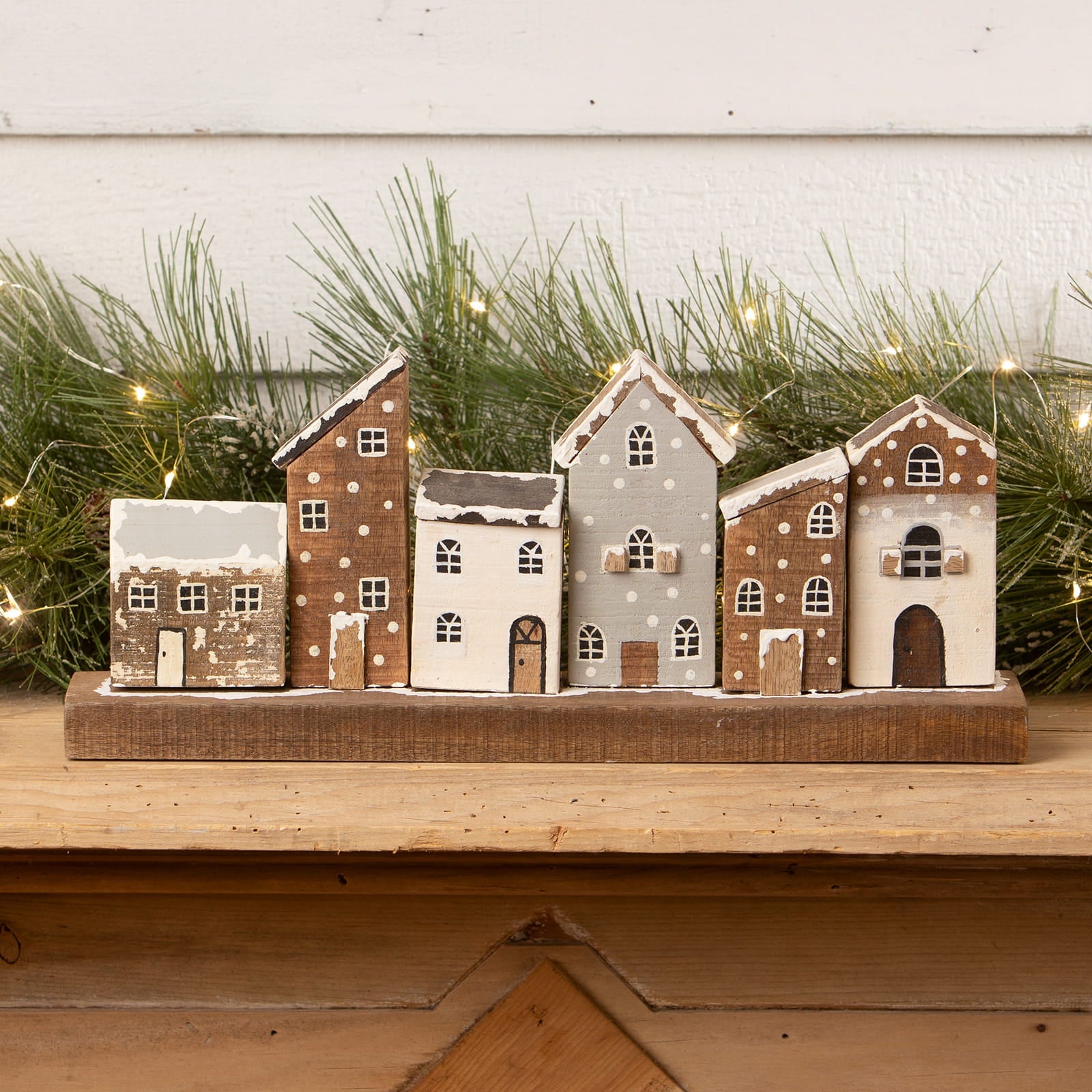 Rustic wooden village with five hand painted miniature houses featuring snowy roofs and white polka dots on wood base