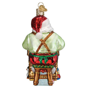 Glass workshop santa ornament with red white hat, light green coat, gold suspenders, seated on shiny red drum christmas glass ornament