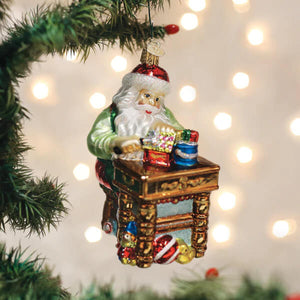 Workshop santa ornament glass santa ornament with red hat green coat and white beard at ornate desk with gifts