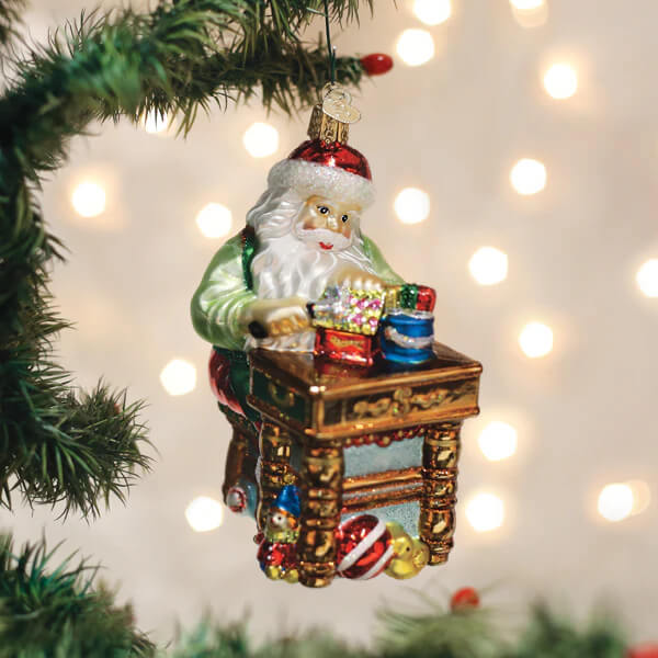 Workshop santa ornament glass santa ornament with red hat green coat and white beard at ornate desk with gifts