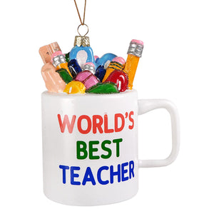 White ceramic measuring cup ornament with worlds best teacher glass ornament text filled with colorful school supplies