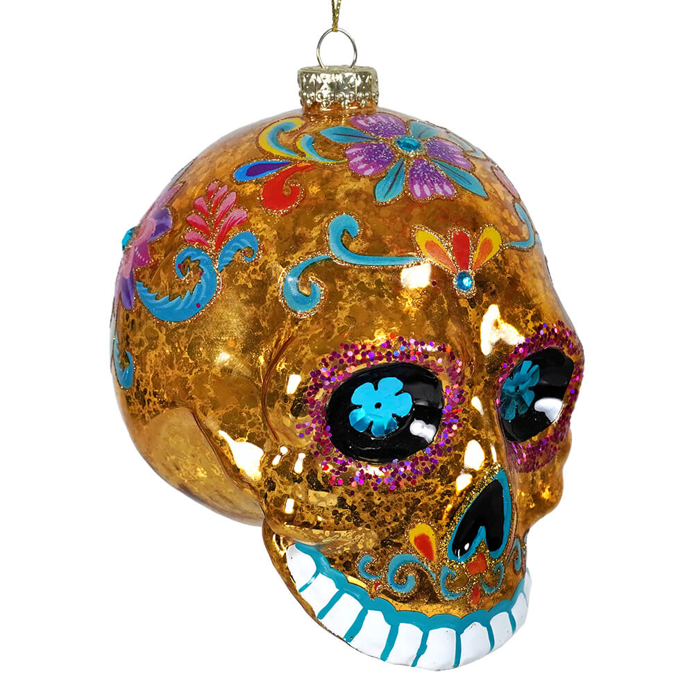 Yellow day dead sugar skull ornament with glittery gold finish colorful floral designs and sparkly eye sockets